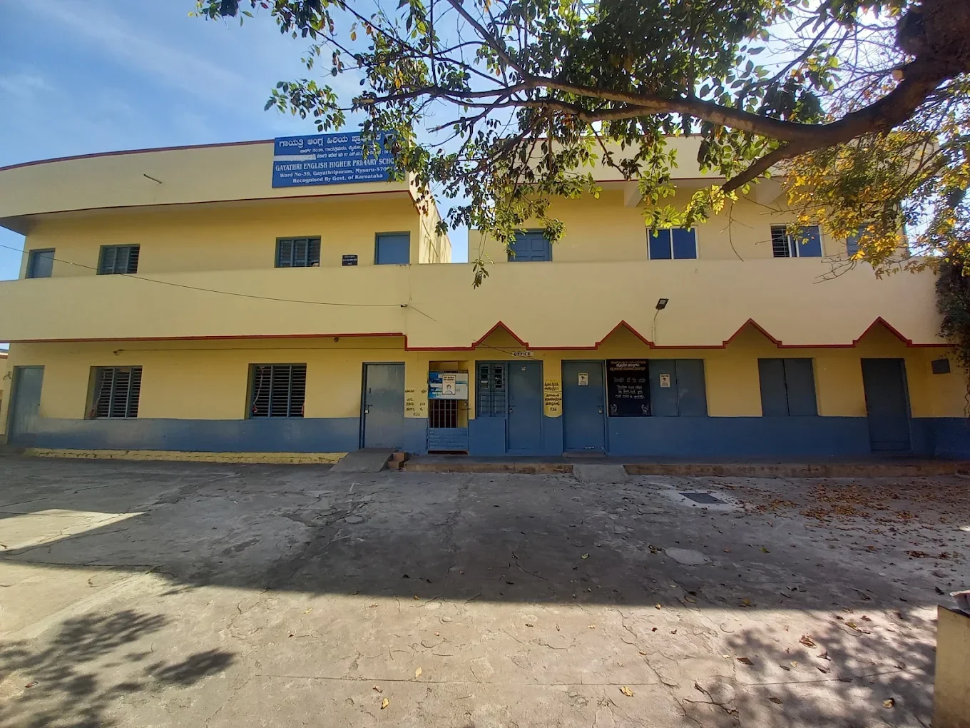 Gayathri Higher Primary School’s yellow building and shaded courtyard in Mysuru