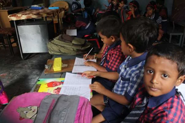 Children writing in exercise books at their classroom desks