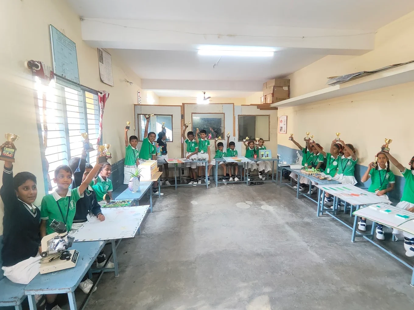 Students holding trophies and sharing their projects at a school exhibition